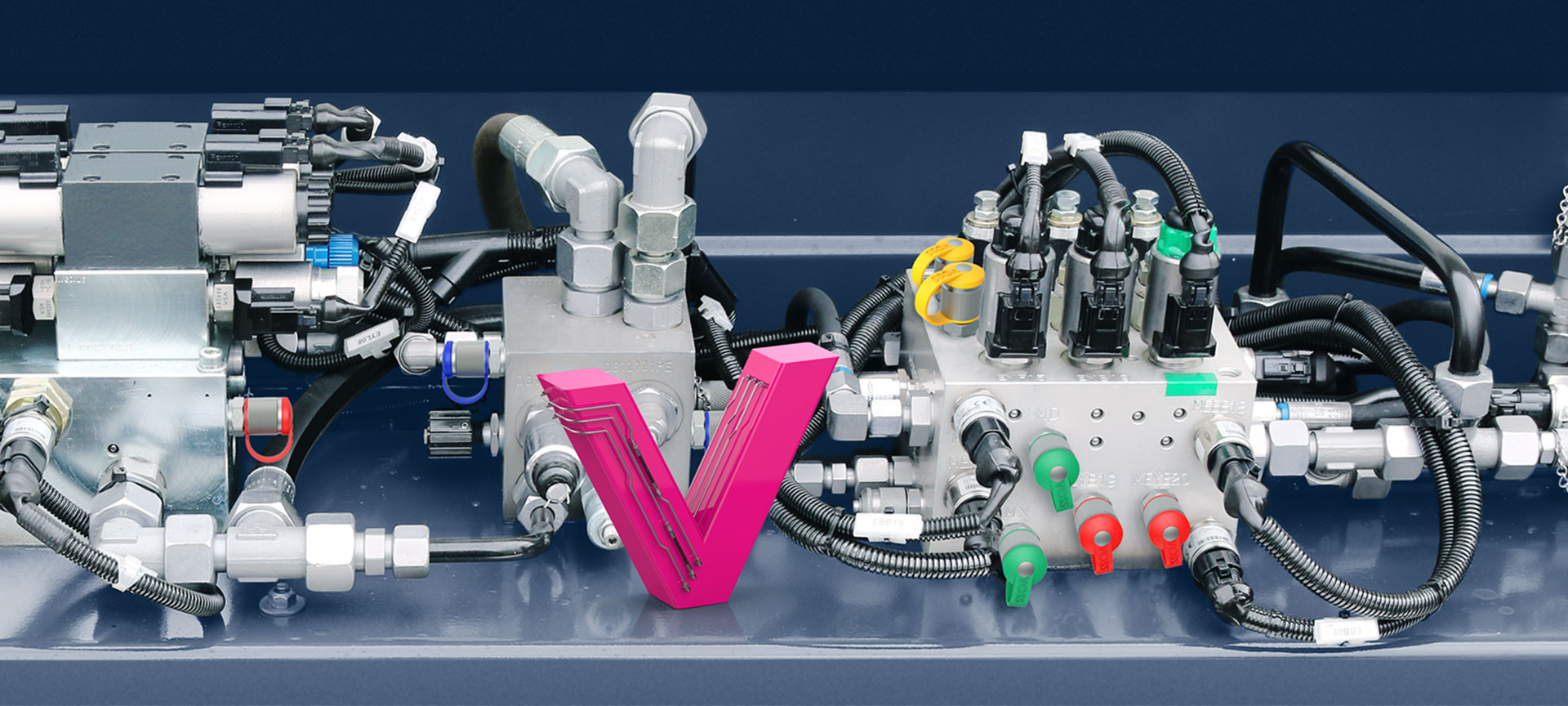 Das Bild zeigt ein magentafarbenes V in miniaturformat in eine Hydraulikanlage arrangiert